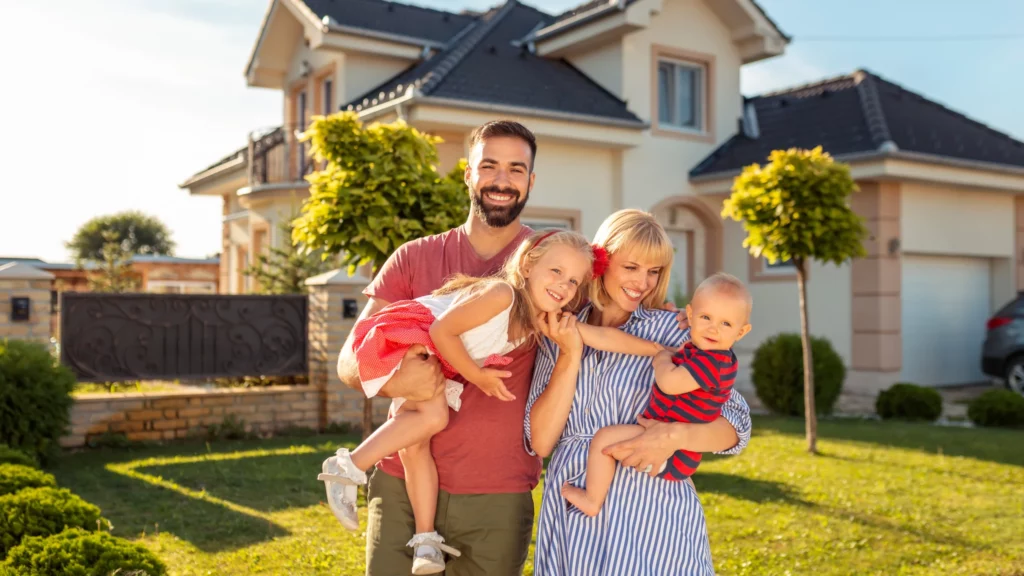A couple with 2 children standing in front of their house.