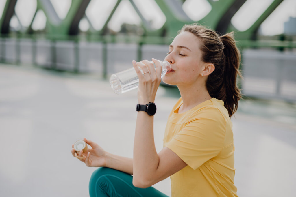Woman drinking water during jog in the city