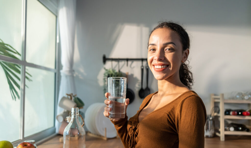 Woman in kitchen drinking water